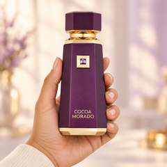 French Avenue Cocoa Morado 100 ml: Hand holding the purple bottle with gold trim in a softly blurred floral interior